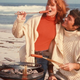 1970s photo of cuddling couple grilling hot dogs on the beach